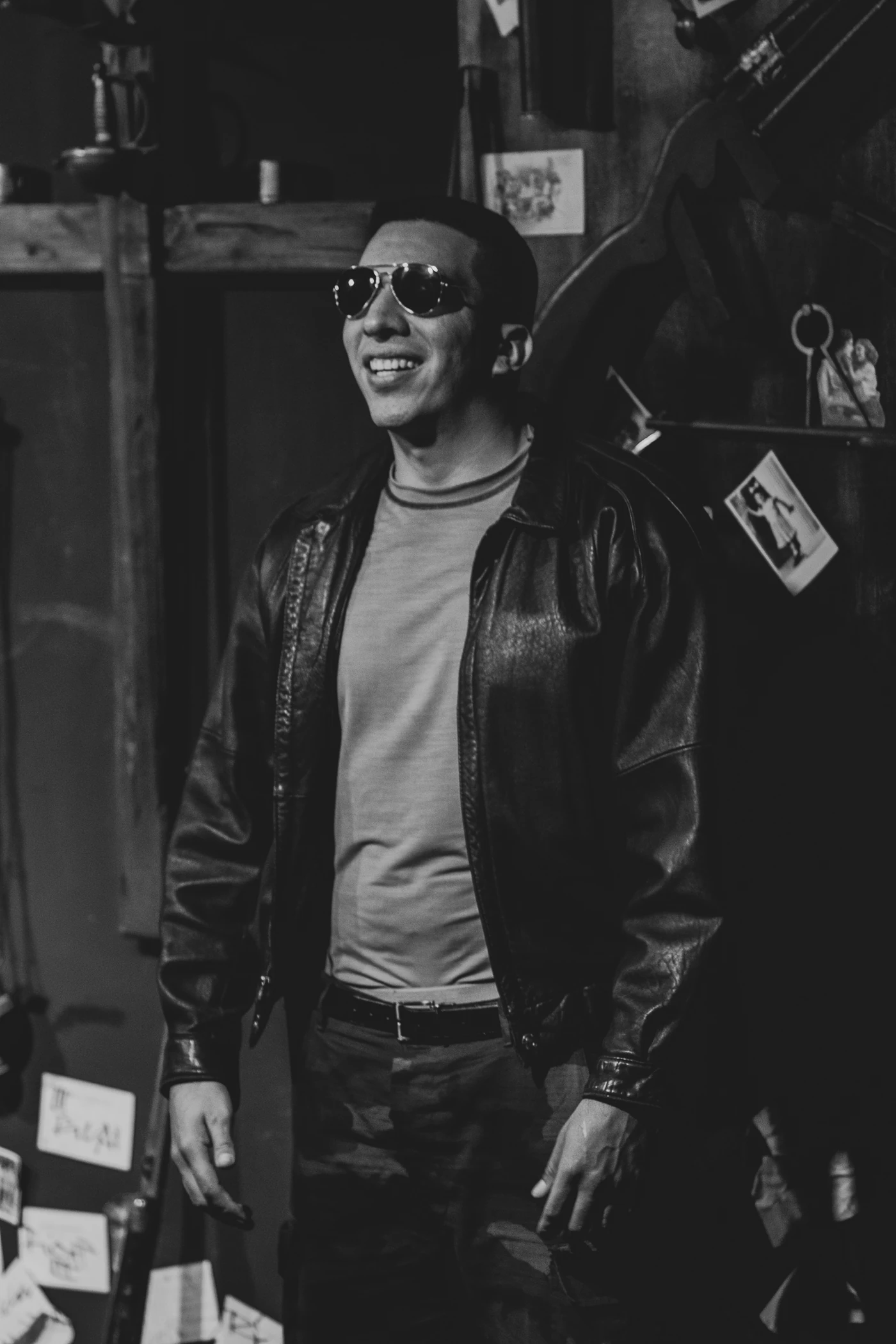 Black-and-white stage photograph of a performer in a cap, sunglasses and leather jacket